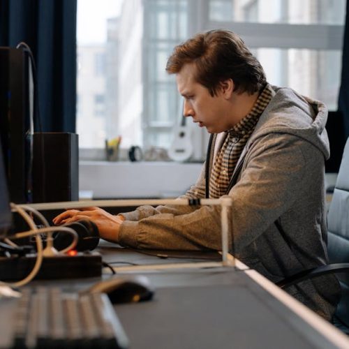 A concentrated professional working at a computer in a modern office setting.